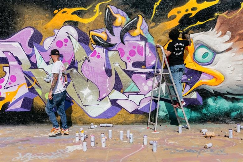 El escritor de graffiti Brus y el artista de tatuaje Victor Chil pintan juntos una producción mural de graffiti